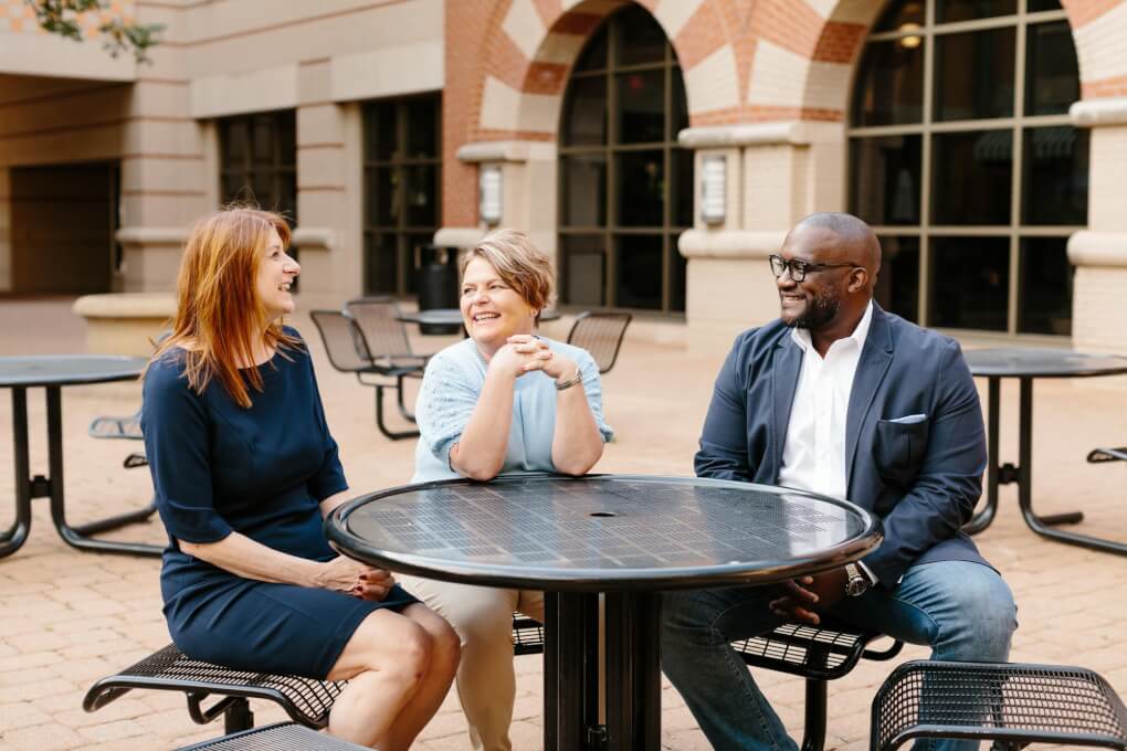 Parks, Zorn and Pierce-Danders chat at a table in the courtyard of the Pew Grand Rapids Campus